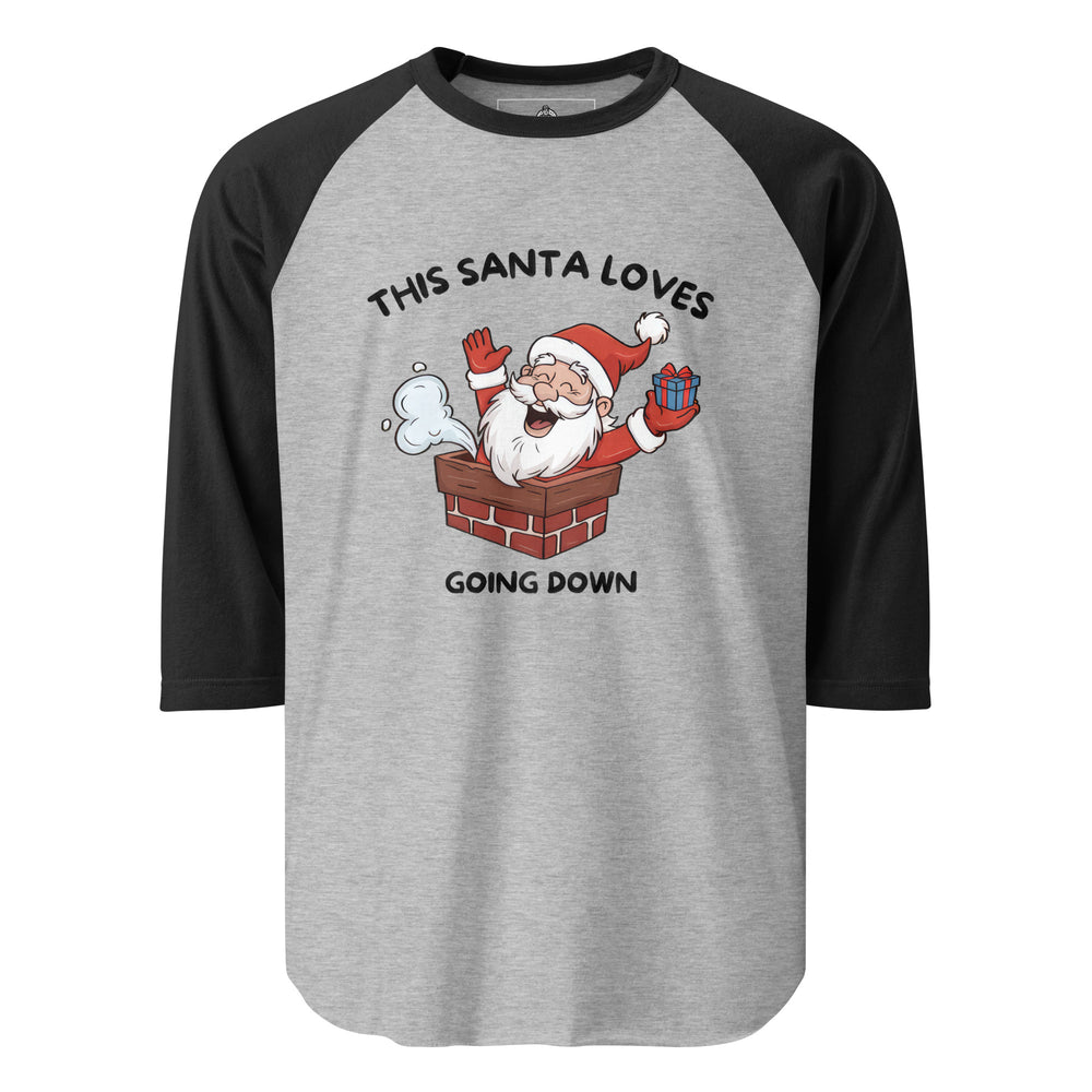 This Santa Loves Going Down — a cheerful Santa popping out of a chimney holding a gift, captioned This Santa Loves Going Down, printed on a 3/4 sleeve raglan shirt.