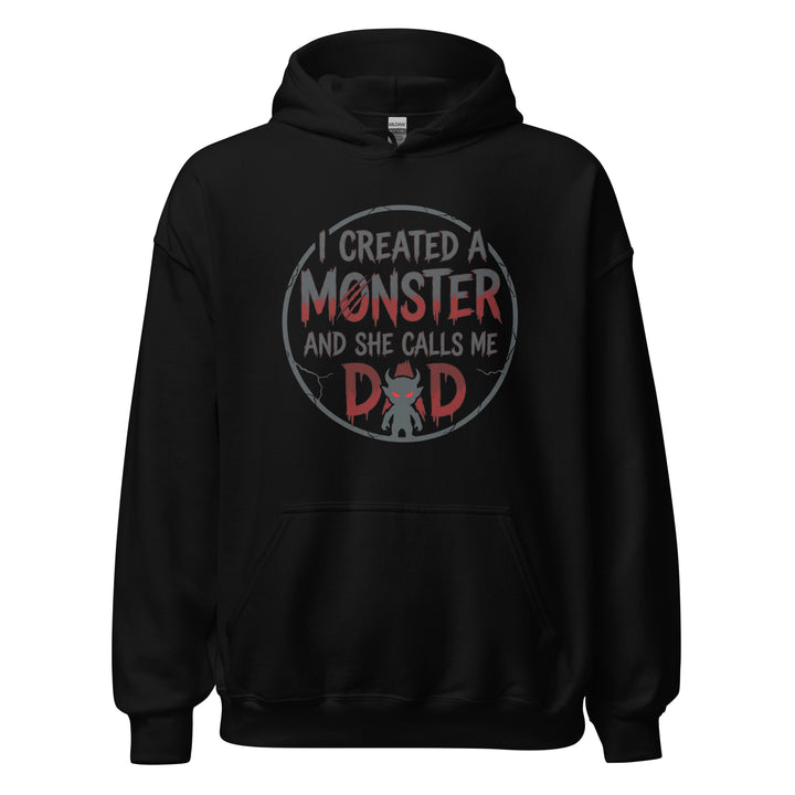 I Created A Monster And She Calls Me Dad funny graphic tee — horror style lettering with a small devil monster forming the A in DAD
