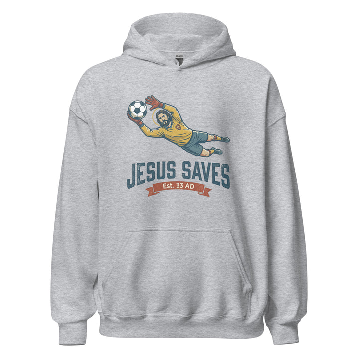 Jesus Saves — Jesus as a soccer goalkeeper diving to catch the ball with a halo, captioned Jesus Saves Est 33 AD, printed on a unisex hoodie.