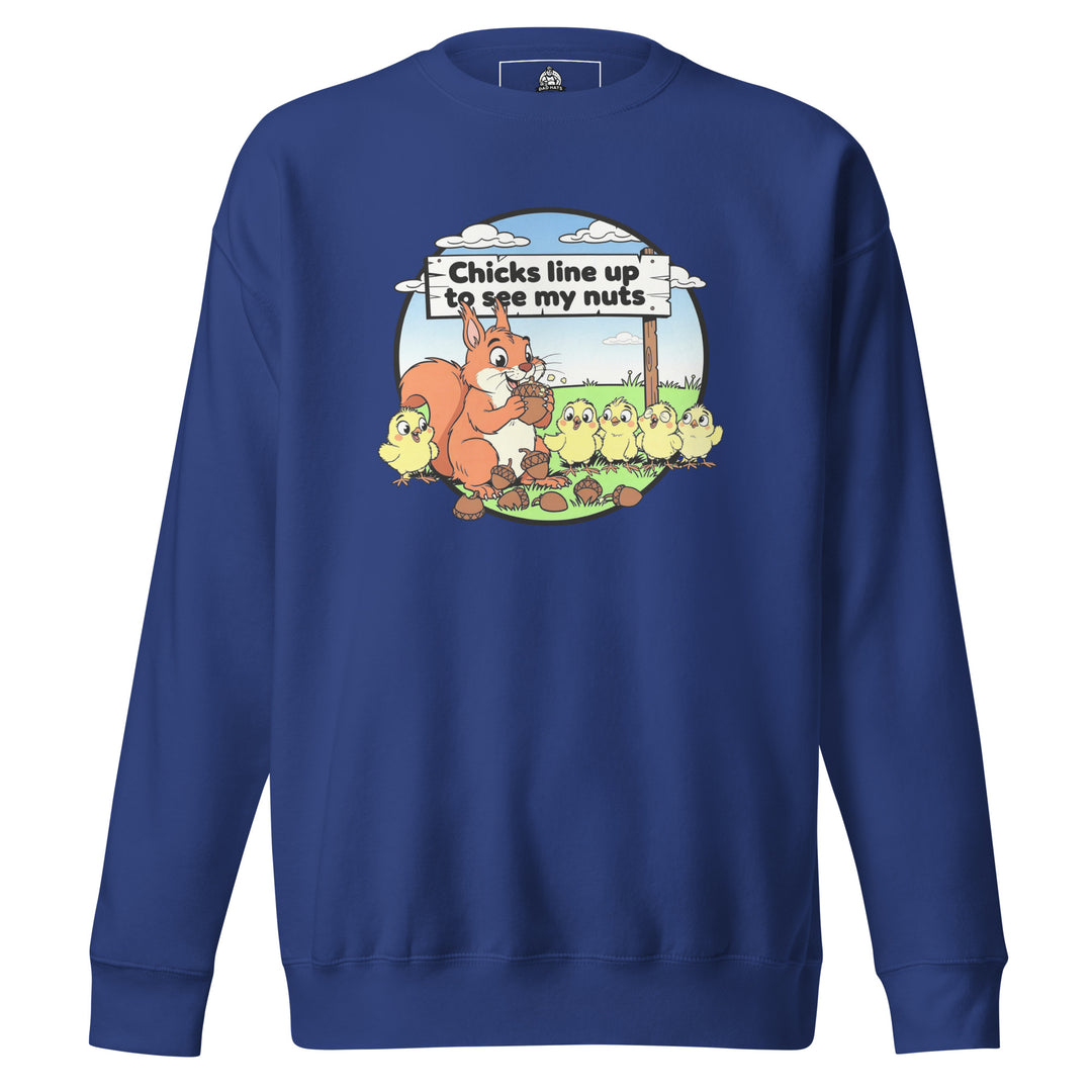 Chicks Line Up To See My Nuts — a cartoon squirrel holding acorns while baby chicks line up behind a sign reading Chicks Line Up To See My Nuts, printed on a unisex sweatshirt.